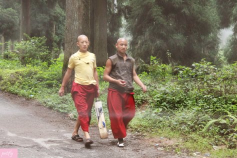 Two teenage monks head to a nearby field to play cricket